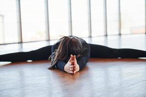 Sporty woman in black sportswear lying down on the floor by doing stretching photo