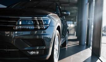 Front part of brand new modern car. Parked at showroom. Reflection in the headlights photo