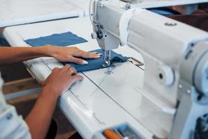 Detailed view of dressmaker woman sews clothes on sewing machine in factory photo