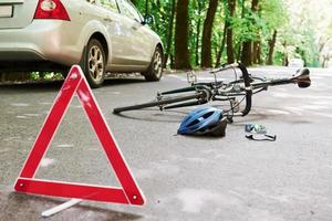 Place of disaster. Bicycle and silver colored car accident on the road at forest at daytime photo