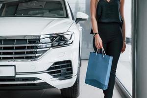 Walking forward. Girl and modern car in the salon. At daytime indoors. Buying new vehicle photo