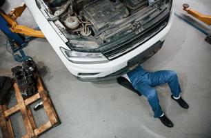 tendido en el suelo. empleado en el uniforme de color azul trabaja en el salón del automóvil foto