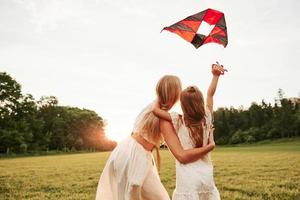 mirando el cielo. madre e hija se divierten con cometas en el campo. Hermosa naturaleza foto