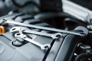 Conception of repairing. Tools lying down on the engine of automobile under the hood photo