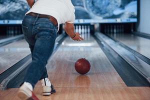 Aquí vamos. vista de partículas traseras del hombre con ropa informal jugando a los bolos en el club foto