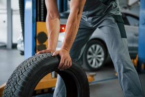 Strong man's hands. Mechanic holds a tire at the repair garage. Replacement of winter and summer tires photo