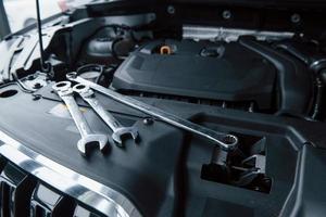 Group of objects. Repair tools lying down on the engine of automobile under the hood photo