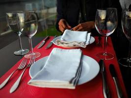 A Person in dark blue dress sitting on dining table, part of body, waiting for dinner serving on wooden table with dinner wear, Gaia, Oporto, Portugal photo