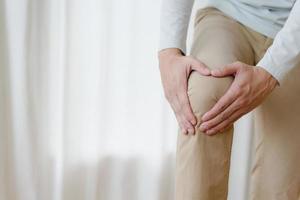 man suffering from pain in knee at home, closeup , healthcare concept photo