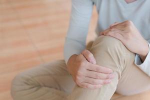 hombre que sufre de dolor en la rodilla en casa, primer plano, concepto de atención médica foto