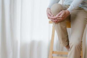 man suffering from pain in knee at home, closeup , healthcare concept photo