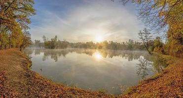 Panoramic image over pond during sunrise with early morning fog photo