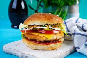 Tasty chicken burger with lettuce, cheese, tomato and pickle. Fast food sandwich with chicken cutlet photo