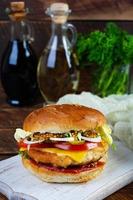 sabrosa hamburguesa de pollo con lechuga, queso, tomate y pepinillo. sándwich de comida rápida con chuleta de pollo