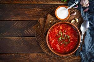 borscht ucraniano tradicional con cebolla verde y crema agria. deliciosa sopa de remolacha en un tazón con pan de centeno. vista superior foto