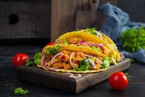 tacos mexicanos con tortilla de maíz. tortilla con carne de pollo, maíz, lechuga y cebolla foto