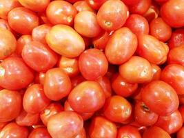 el primer plano y el montón de cultivos de tomate pequeño se ajustan al fondo de la pantalla foto
