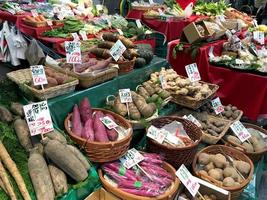 verduras frescas y raíces puestas en los estantes del mercado kuromon ichiba para esperar a que los clientes compren para cocinar en casa. foto