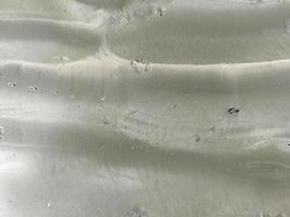 closeup texture of gray sand beach background with sun light on summer photo
