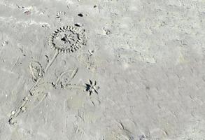 Forma de flores de sol de primer plano hecha de playa de arena gris con luz solar en verano foto