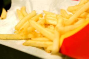 French fries from fast food on white paper and black background. photo