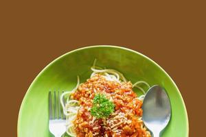 Top view of spaghetti tomato sauce and minced pork look tasty with spoon and fork on ceramic plate and brown background. Make with paths photo