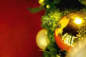 primer plano de bolas de navidad doradas decoradas en pino el día de navidad y fondo rojo foto