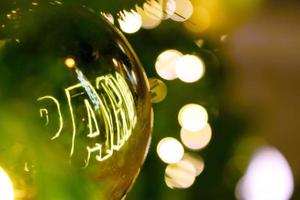 Closeup golden Christmas Balls Decorated on Pine Tree on Christmas day with bokeh of led lighting and blurry background. photo