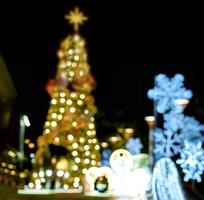 vista borrosa y bokeh del árbol de navidad y decorar la iluminación led frente al centro comercial en la noche de navidad en la ciudad urbana. foto