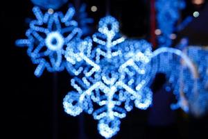 Blurred and bokeh decorated led of Christmas blue lighting in snowflake shape on night time and blurry background. photo