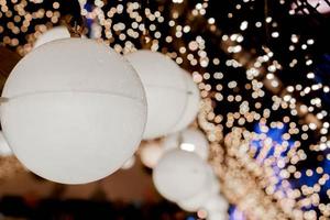 el primer plano decora las lámparas navideñas que cuelgan las luces interiores del túnel en un borroso y bokeh de relámpagos de reflexión led en el fondo nocturno. foto