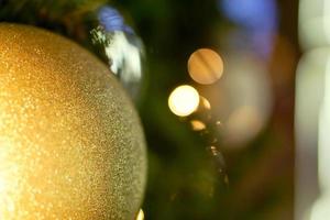 Closeup golden Christmas Balls Decorated on Pine Tree on Christmas day with bokeh of led lighting and blurry background. photo