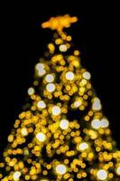 busque la vista borrosa y el bokeh de la iluminación navideña en el árbol de navidad y el fondo negro. foto