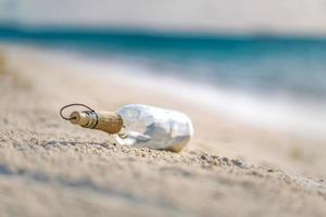 Message in the bottle washed ashore against the sun setting down. Bottle with a message photo