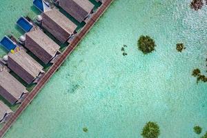 Aerial view of Maldives luxury water villas with infinity pools. Exotic landscape, top view, aerial landscape beach. Perfect Maldives island background, amazing scenery, soft green blue sea color photo