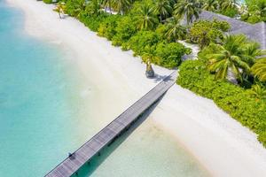 Aerial landscape of Maldives beach. Tropical panorama, luxury water villa resort with wooden pier or jetty. Luxury travel destination background for summer holiday and vacation concept. photo