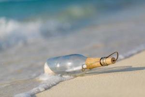 Message in the bottle washed ashore against the sun setting down. Bottle with a message photo