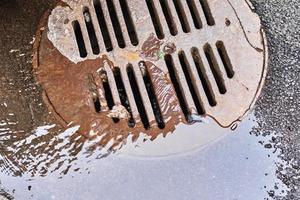 Water draining into a sewer manhole after rain on the city street photo