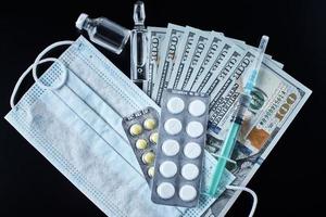 Pills, protective mask, medical items and dollar bills on dark background. photo
