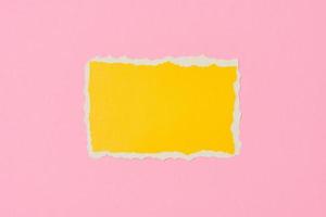 Ripped yellow paper torn edge sheet on a pink background.