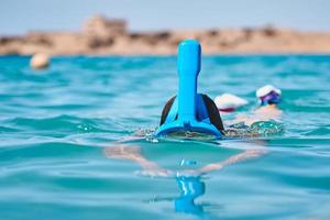 mujer con una máscara facial completa de snorkel buceando en el mar azul. vacaciones de verano