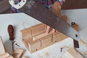 proceso de manos de carpintero aserrando una tabla de madera foto