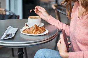 Woman have breakfast in caffe and using smartphone photo