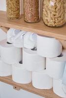 existencias de rollos de papel higiénico, máscara protectora y productos en el estante en casa foto