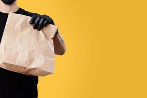 el repartidor sostiene una bolsa de papel con comida. concepto de entrega de alimentos foto