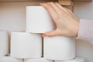 Woman hand take toilet paper woll from shelf photo