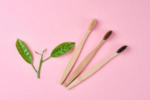 Bamboo toothbrushes on pink background. Zero waste concept photo