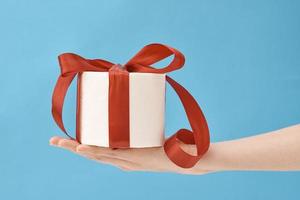 hand hold toilet paper wrapped in festive ribbon as gift on blue background photo