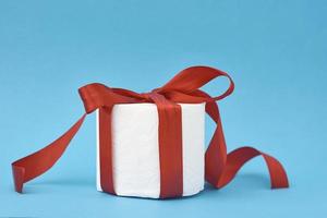 papel higiénico envuelto en cinta roja festiva como regalo sobre fondo azul foto