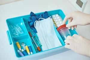 Hands in medical gloves take test cup from medicine box photo